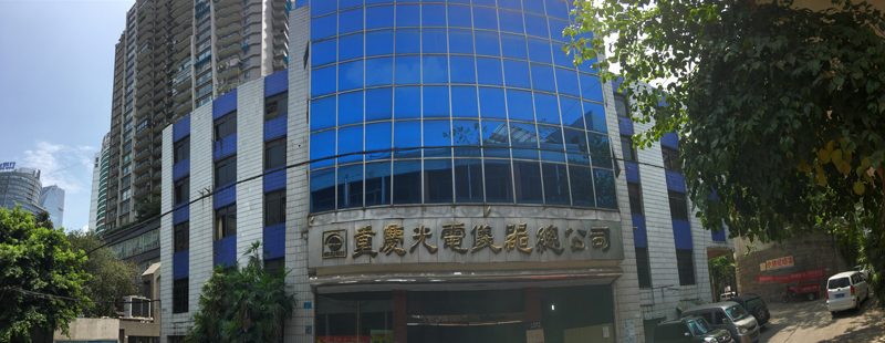 The head office, a curved blue mirrored-glass building with gold characters reading Chongqing Optical and Electrical Instrument General Company